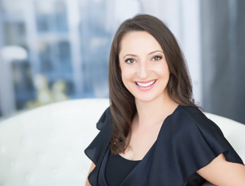 Lauren Goldstein professional headshot, smiling in a black ruffled top against a soft light background